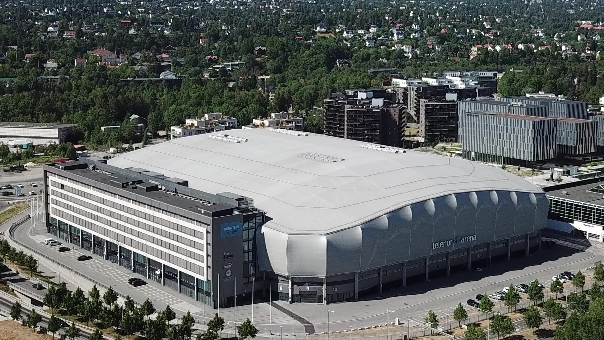 Unity Arena sett fra luften med parkering, fasade og omgivelser på Fornebu